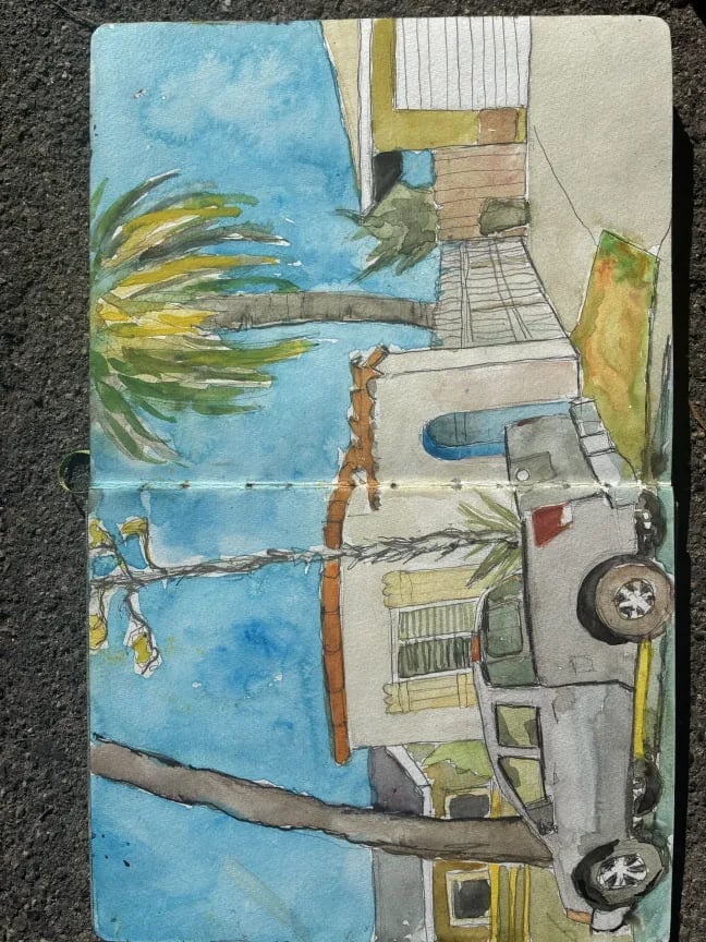 Hand-drawn illustration on tiled paper showing a tropical scene with palm tree, ocean, beach hut, and vintage truck