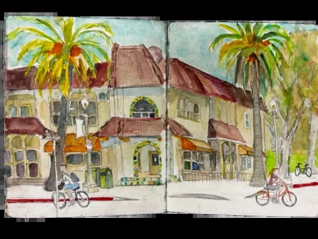 Watercolor sketch of a Mediterranean-style building with palm trees and bicycles parked on the street, open sketchbook spread